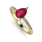 Front three-quarter studio view of the Calista ruby ring, highlighting the brilliant white pavé diamonds set into the warm, rich yellow gold shoulders.