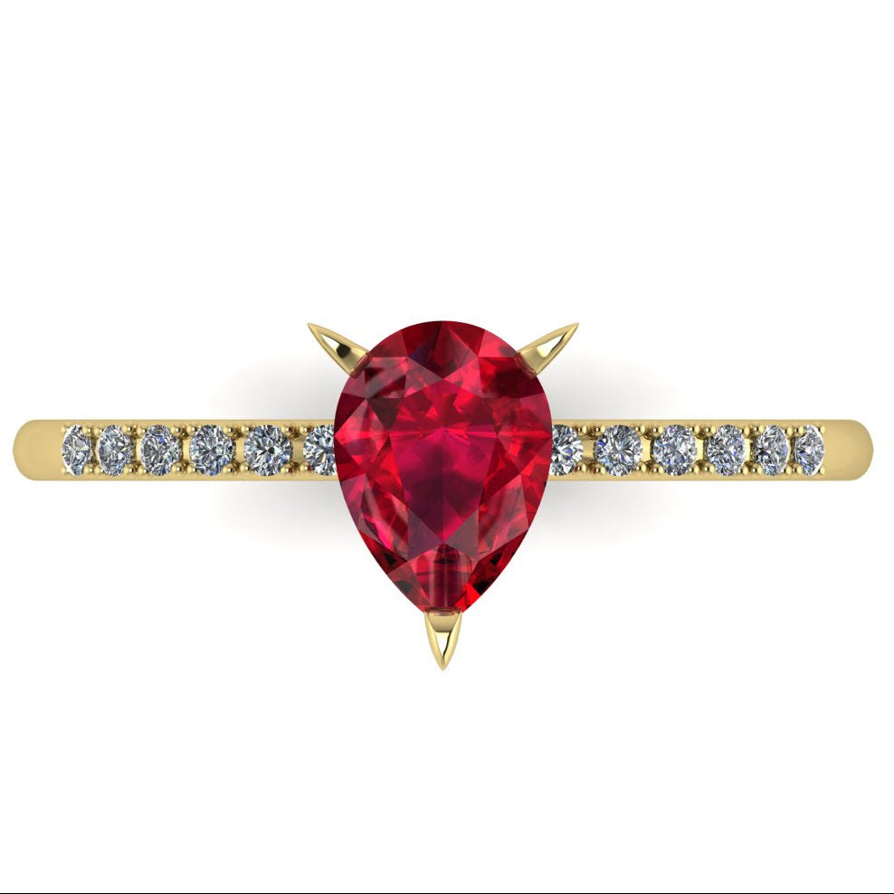 Top-down studio hero shot of the Calista engagement ring, showcasing a vibrant pear-shaped red ruby on a polished yellow gold band with diamond shoulders.