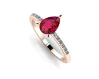 Front three-quarter studio view of the Calista ruby ring, showcasing the brilliant white pavé-set diamonds gleaming on the warm rose gold shoulders.