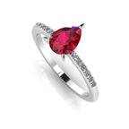 Front three-quarter studio view of the Calista ruby ring, highlighting the brilliant white pavé diamonds set into the polished white metal shoulders.