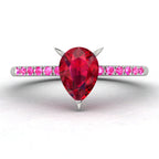 Calista engagement ring, showcasing a prominent pear-shaped red ruby on a white gold or platinum band with vibrant pink sapphire shoulders.