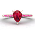 Front view studio hero shot of the Calista engagement ring, showcasing a prominent pear-shaped red ruby on a rose gold band with vibrant pink sapphire shoulders.