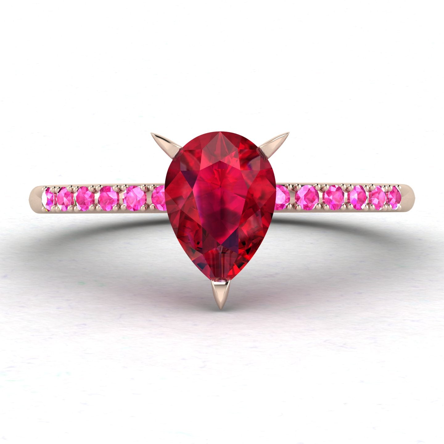 Front view studio hero shot of the Calista engagement ring, showcasing a prominent pear-shaped red ruby on a rose gold band with vibrant pink sapphire shoulders.