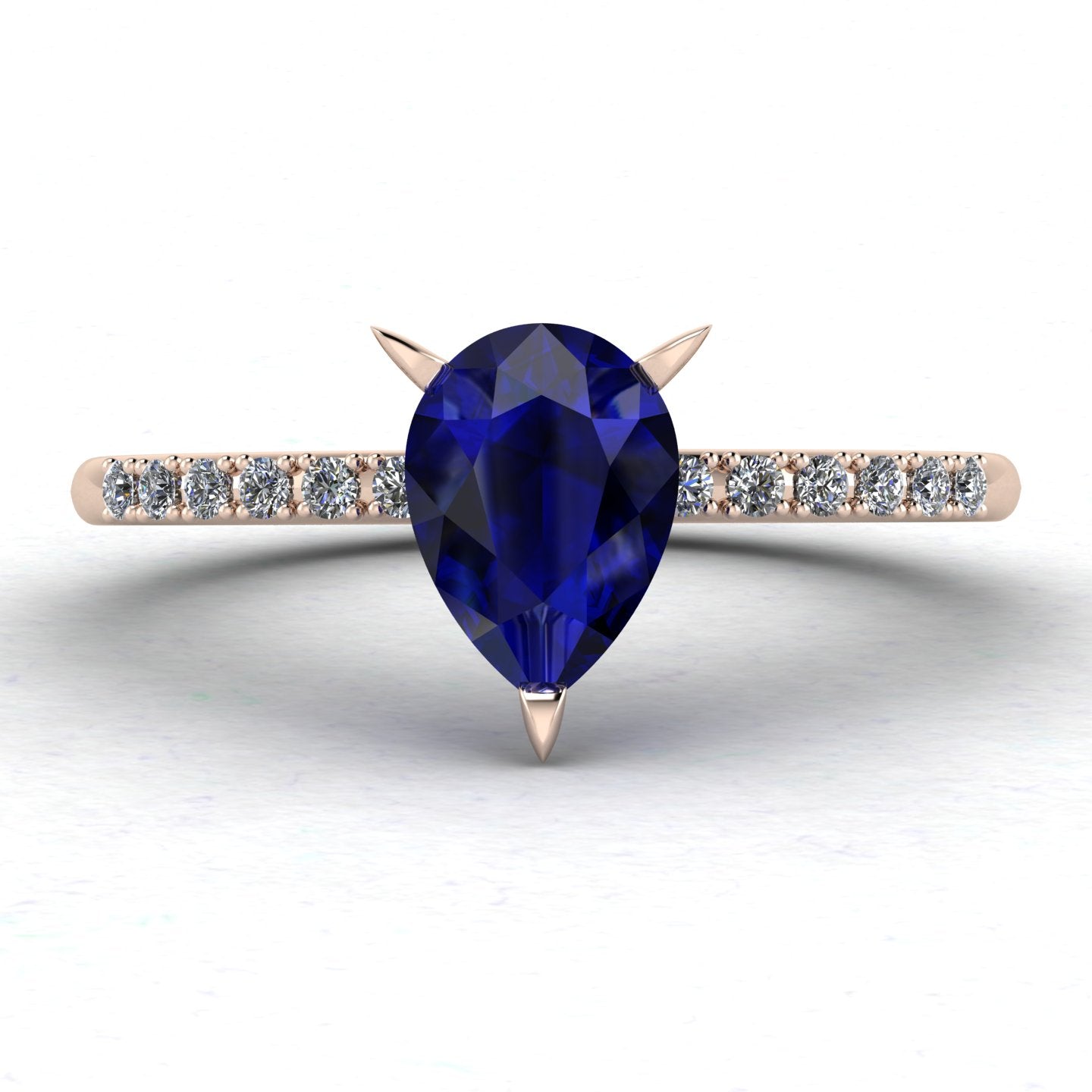 Front studio hero shot of the Calista engagement ring, featuring a prominent pear-shaped blue sapphire on a rose gold band with sparkling white diamond shoulders.