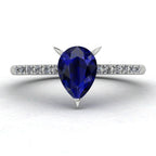 Front view of the Calista engagement ring, showcasing a prominent pear-shaped blue sapphire on a polished white gold or platinum band with diamond shoulders.