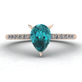 Top-down studio hero shot of the Calista 18ct rose gold ring, featuring a rich pear-shaped teal sapphire and diamonds.