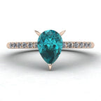 Top-down studio hero shot of the Calista 18ct rose gold ring, featuring a rich pear-shaped teal sapphire and diamonds.