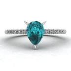 Front view hero shot of the Calista 18ct white gold ring, featuring a rich pear-shaped teal sapphire surrounded by a halo of white diamonds.
