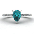 Front view hero shot of the Calista 18ct white gold ring, featuring a rich pear-shaped teal sapphire surrounded by a halo of white diamonds