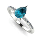 Front three-quarter studio view of the Calista 18ct white gold ring, showcasing the pear-cut teal sapphire and diamond-set shoulders