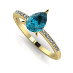 Front three-quarter studio view of the Calista 18ct gold ring, showcasing the pear-cut teal sapphire and diamond-set shoulders.