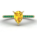 Calista engagement ring in 18ct yellow gold, showcasing the striking colour contrast between the pear-shaped yellow sapphire and surrounding green emeralds.