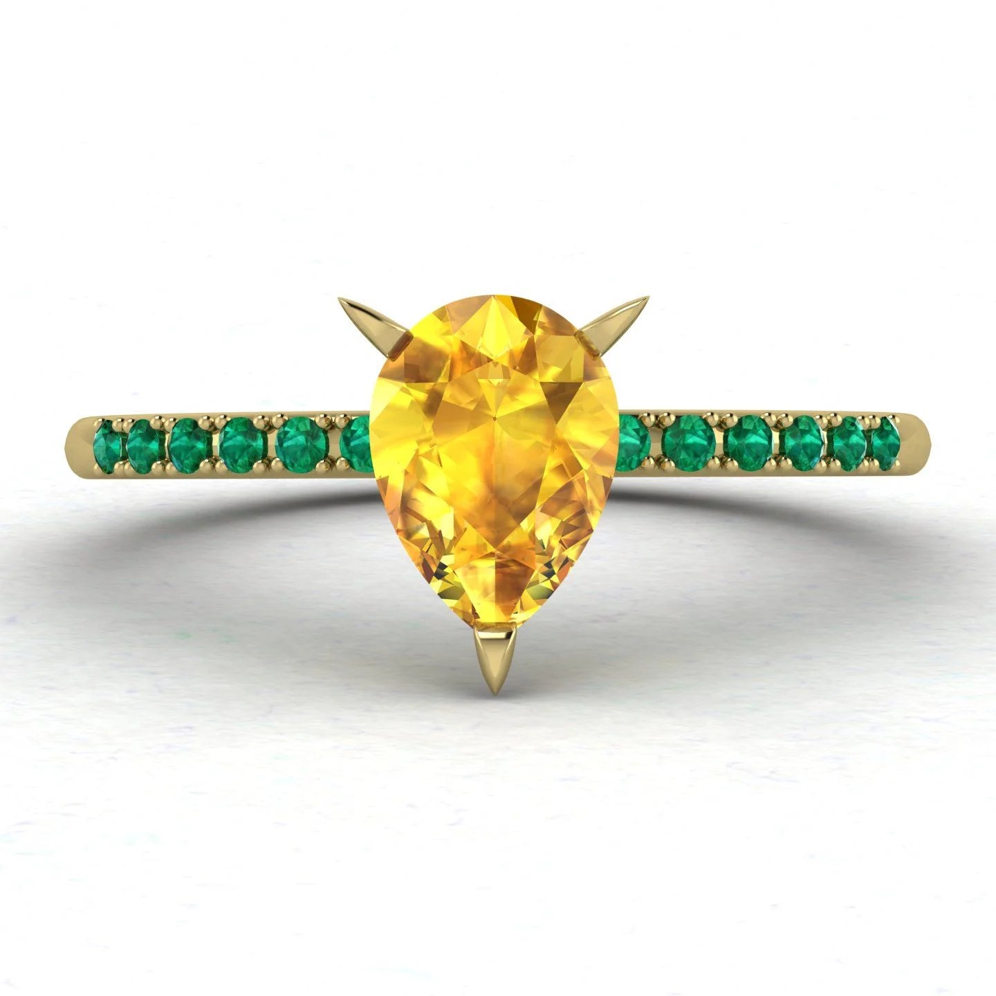 Calista engagement ring in 18ct yellow gold, showcasing the striking colour contrast between the pear-shaped yellow sapphire and surrounding green emeralds.