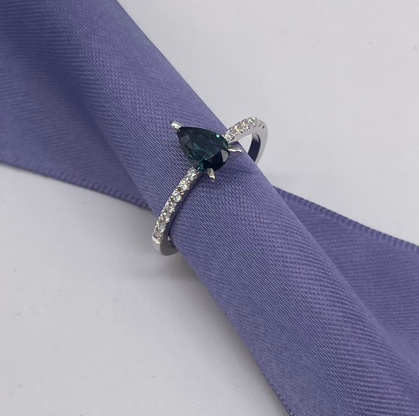 Calista engagement ring in 18ct white gold, capturing the cool, icy ocean sparkle of the pear-shaped teal sapphire and brilliant white diamonds.