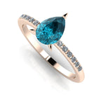 Front three-quarter studio view of the Calista 18ct rose gold ring, showcasing the pear-cut teal sapphire and diamond-set shoulders.