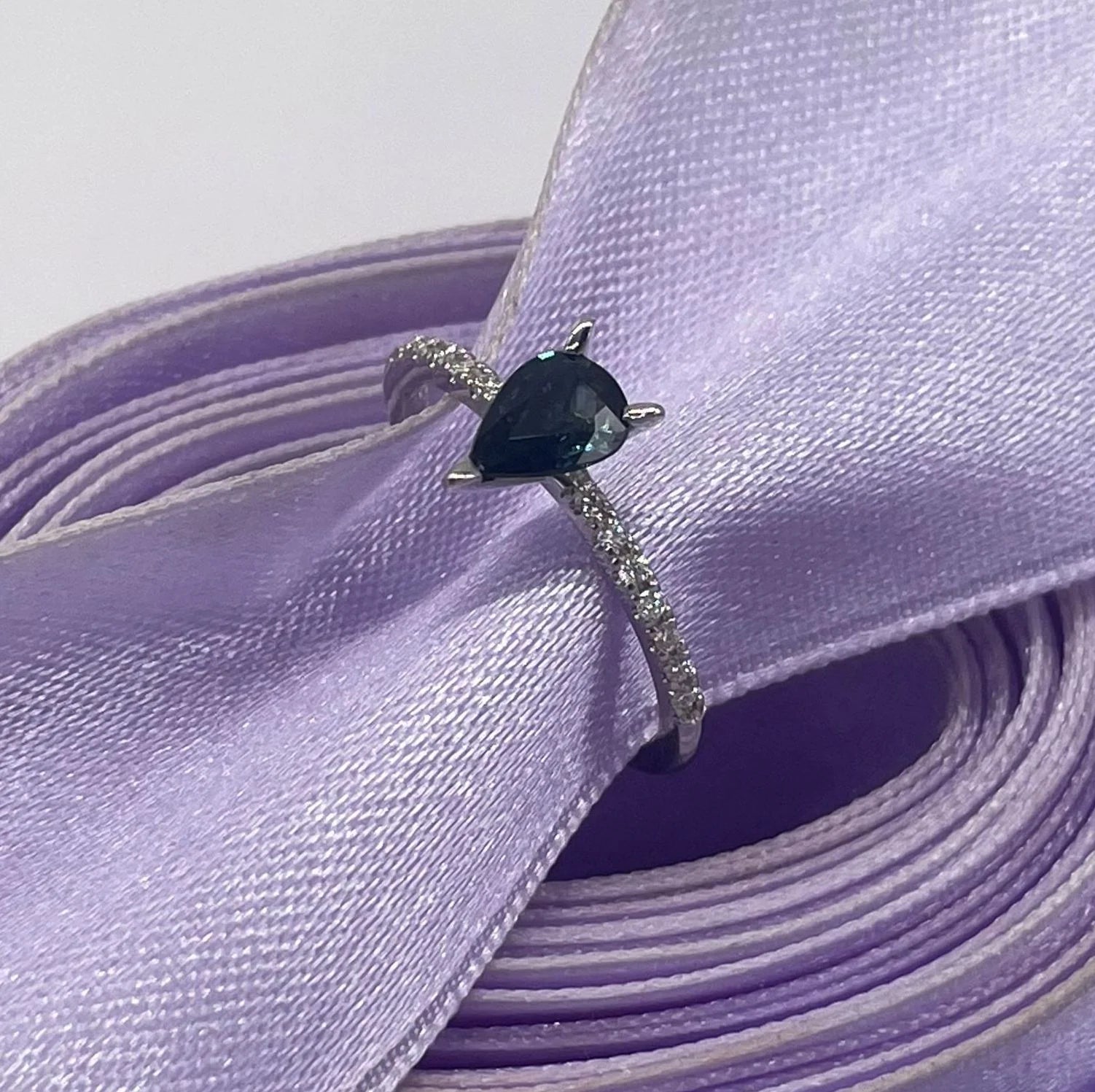 Calista engagement ring in 18ct white gold, capturing the cool, icy ocean sparkle of the pear-shaped teal sapphire and brilliant white diamonds.