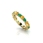 Detailed close-up of the marquise-cut green emeralds and bright yellow sapphires set in a contemporary eternity band.