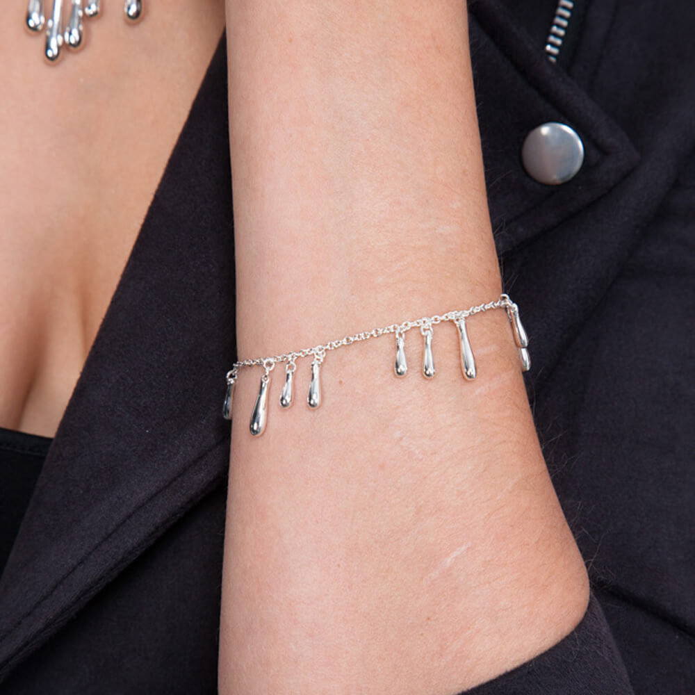 Cluster Drop Silver Bracelet in sterling silver — model wearing bracelet on wrist against dark jacket, showing polished droplet charms in motion
