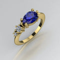 Angled view of the Comet yellow gold ring, featuring a pear-shaped deep blue sapphire with two smaller round white diamonds set along one shoulder.