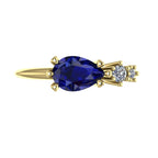 Top view of the Comet yellow gold ring, showing an east-west pear-shaped blue sapphire beside two graduated round white diamonds in an asymmetric arrangement.