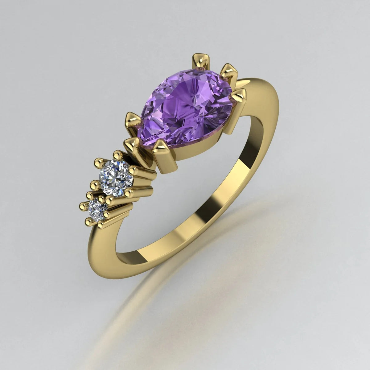 Angled view of the Comet yellow gold ring, featuring a pear-shaped violet sapphire with two smaller round white diamonds set along one shoulder.