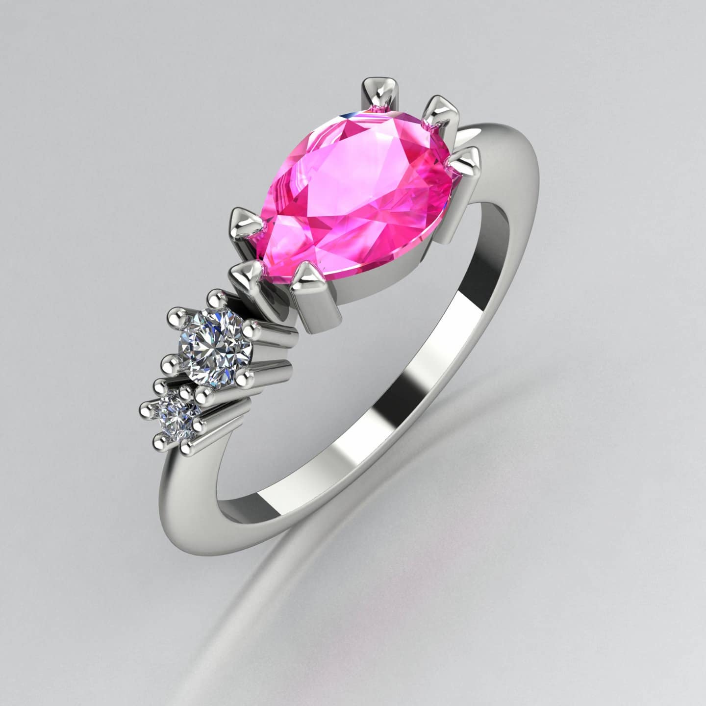 Comet asymmetrical engagement ring in 18ct white gold with a horizontally set pear shaped pink sapphire and two graduating diamonds, handmade in our London studio