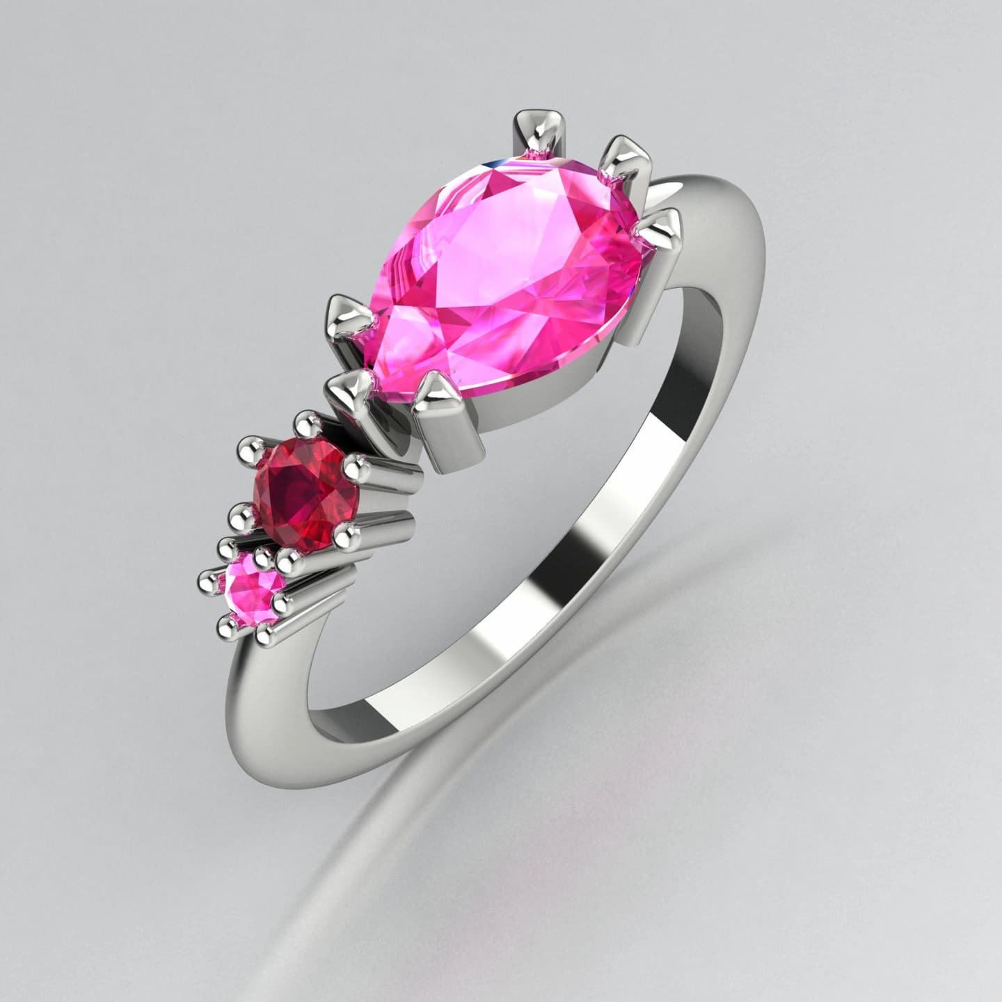 Asymmetrical Comet engagement ring in 18ct white gold with a pear shaped pink sapphire, round ruby and round pink sapphire, handmade in our London studio