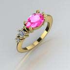 Angled view of the Comet yellow gold ring, featuring a pear-shaped pink sapphire with two graduated round white diamonds along one shoulder.