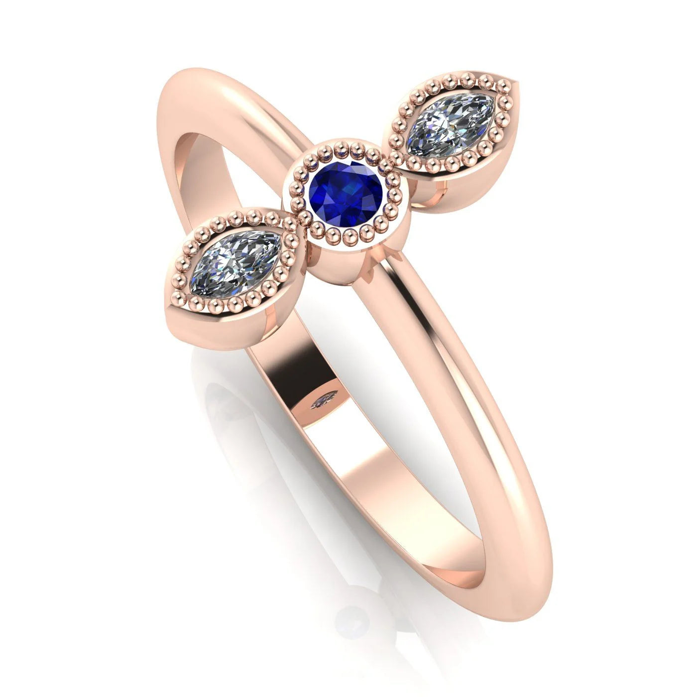 Angled perspective of an 18ct rose gold trilogy ring with a diamond and blue sapphires featuring fine milgrain textured edges.