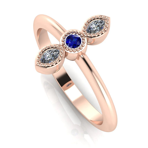 Angled perspective of an 18ct rose gold trilogy ring with a diamond and blue sapphires featuring fine milgrain textured edges.