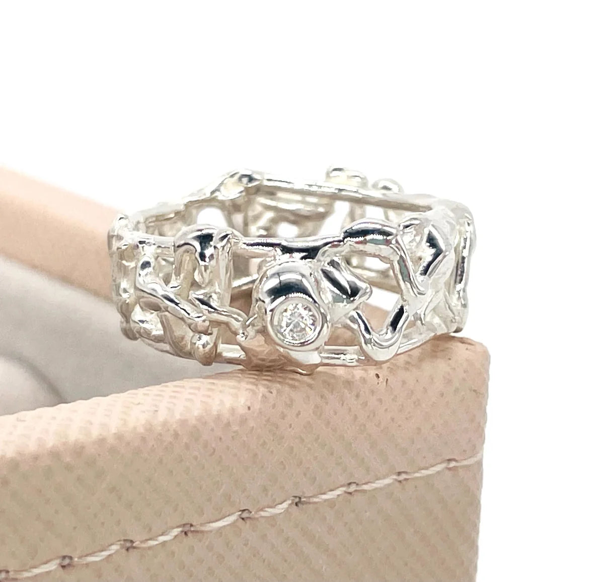 Origin Honeycomb Ring in sterling silver with a brilliant-cut diamond, shown on a beige jewellery box