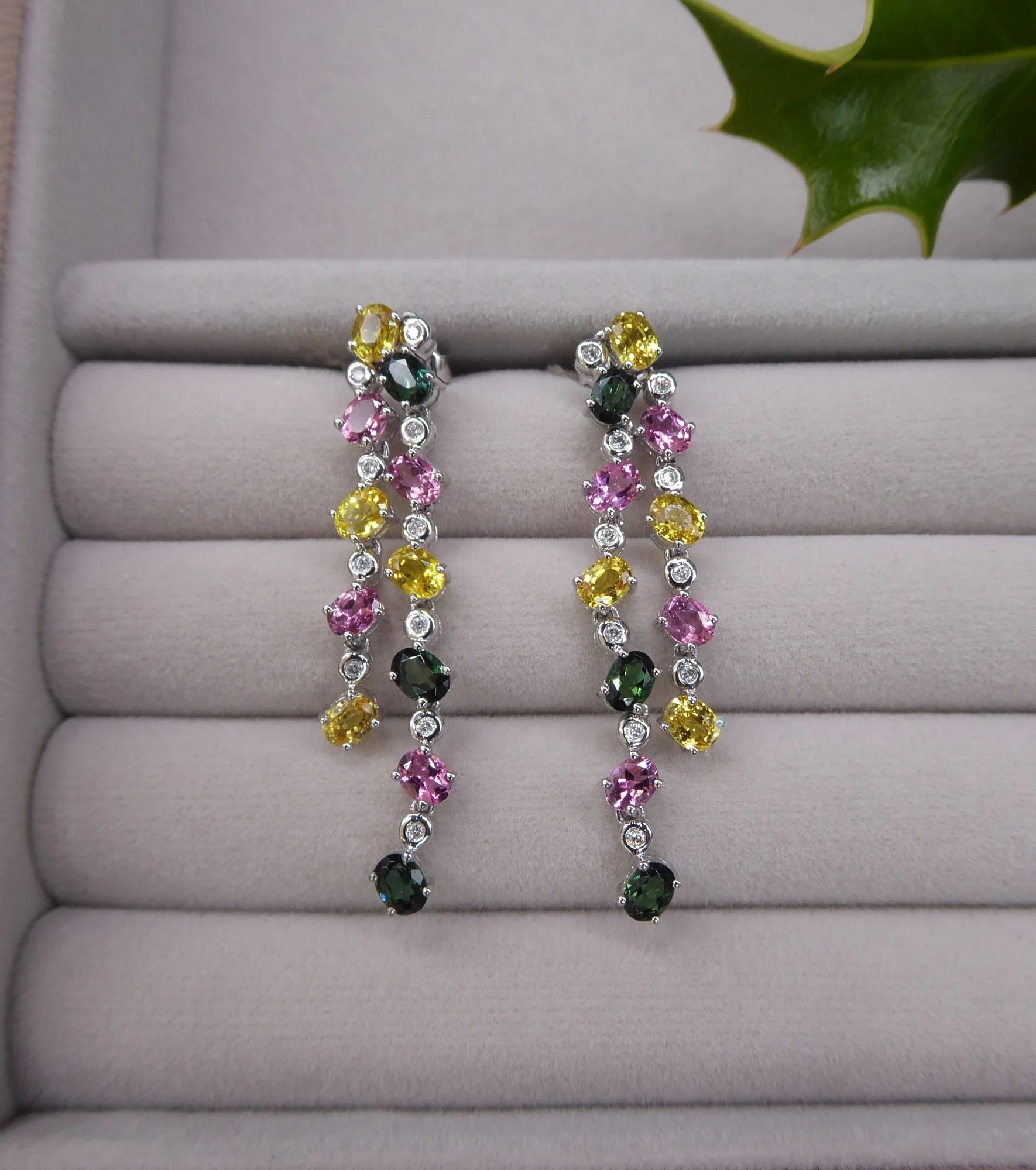 lifestyle view of the double-drop earrings, highlighting the sparkle of the diamonds and gemstones on velvet tray.