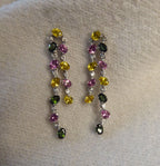 lifestyle view of the double-drop earrings, highlighting the sparkle of the diamonds and gemstones on textile background.