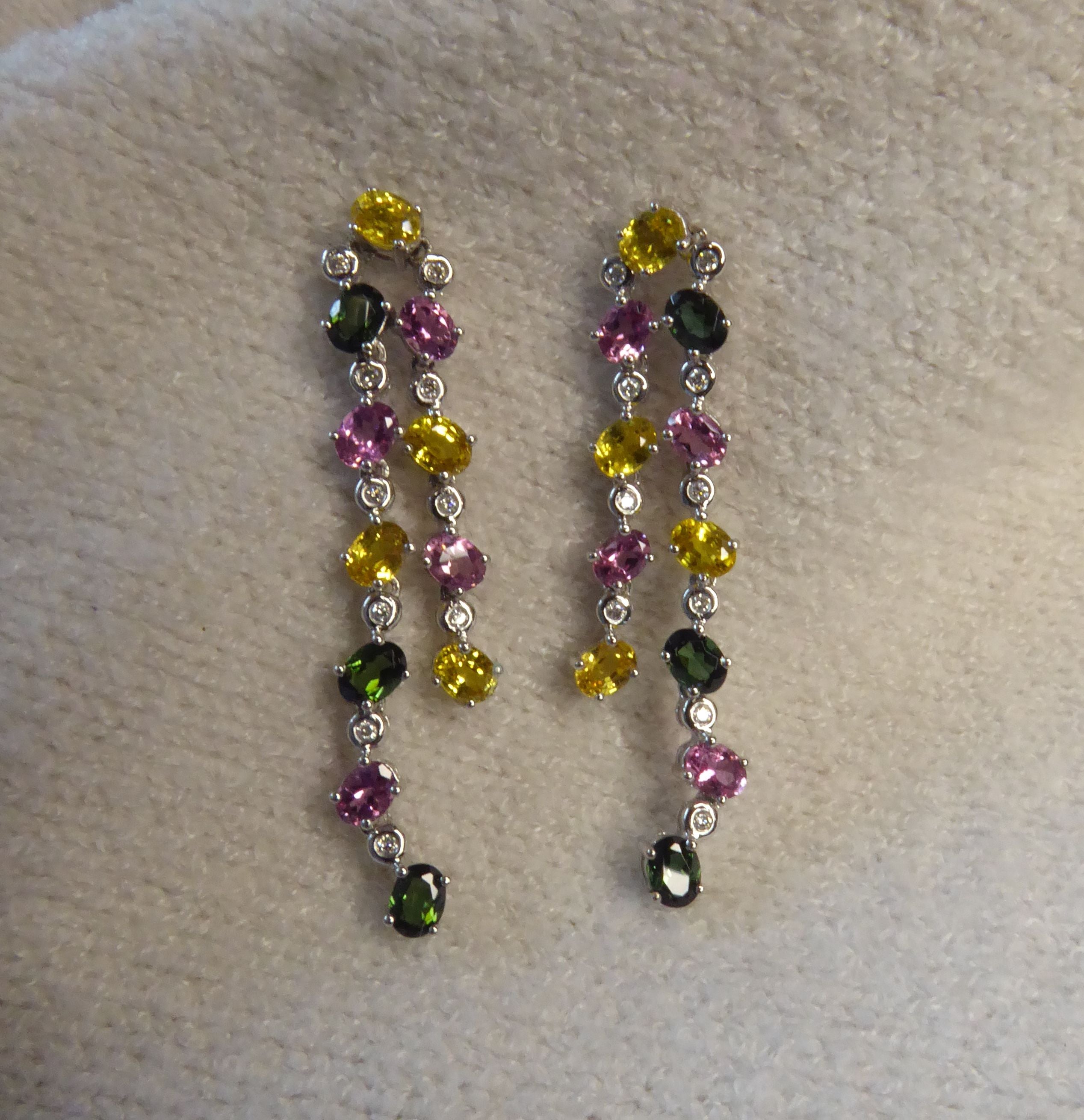 lifestyle view of the double-drop earrings, highlighting the sparkle of the diamonds and gemstones on textile background.