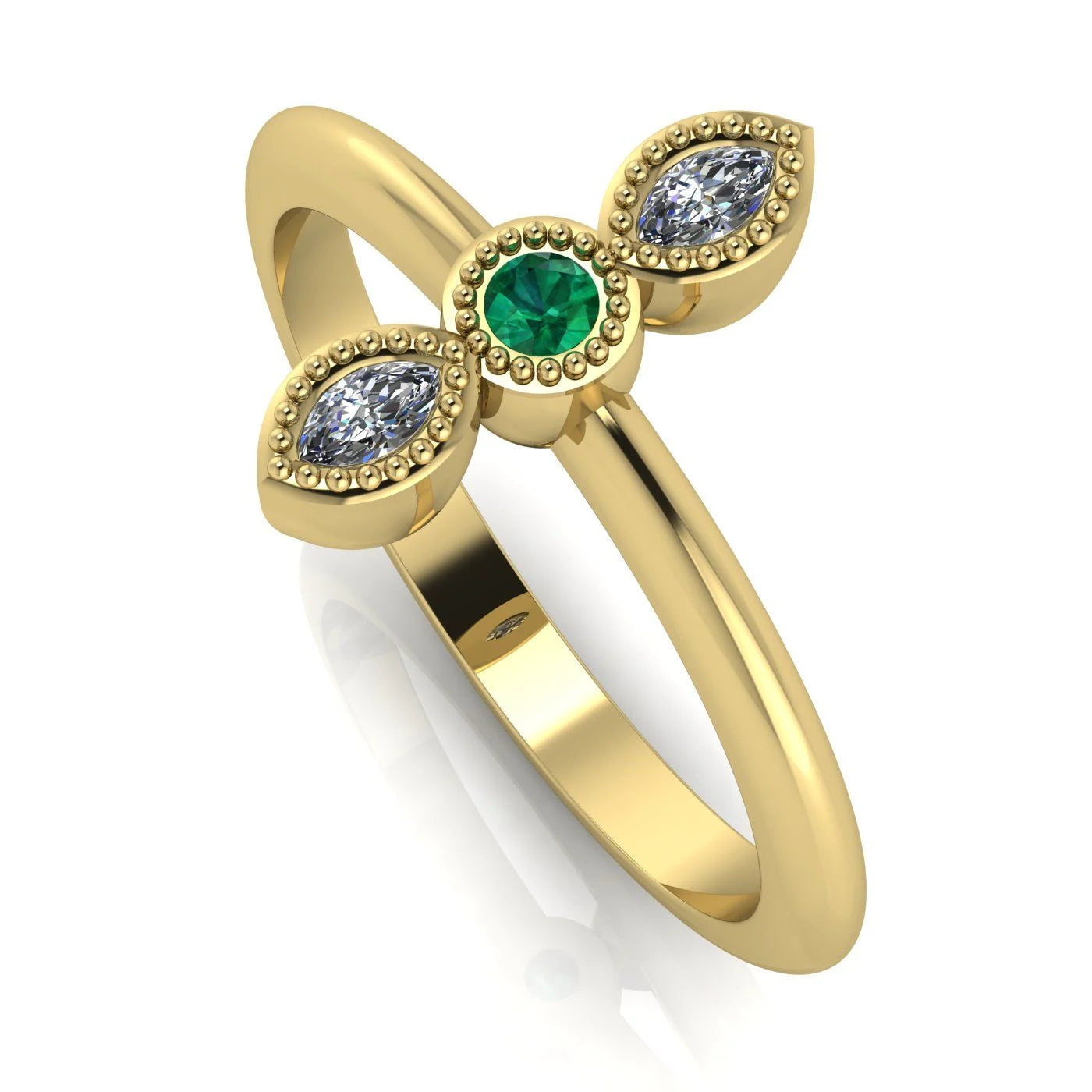 Angled perspective of an 18ct yellow gold trilogy ring with an emerald and diamonds featuring fine milgrain textured edges.