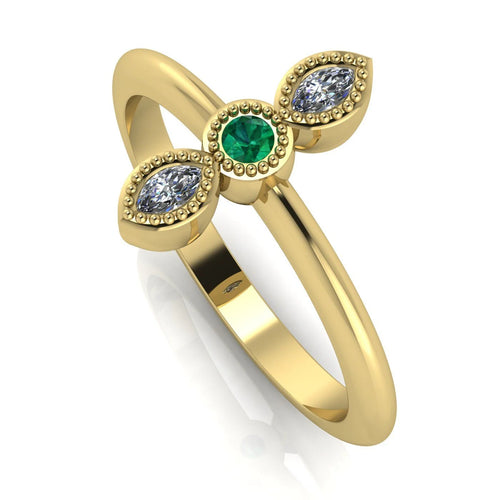 Angled perspective of an 18ct yellow gold trilogy ring with an emerald and diamonds featuring fine milgrain textured edges.