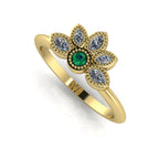 Angled view of an emerald and marquise diamond cluster ring in 18ct yellow gold with textured beaded details.