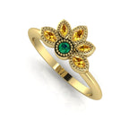 Angled view of an emerald and yellow sapphire cluster ring in 18ct yellow gold with milgrain textured edges.