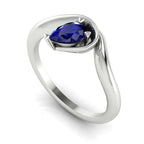 Enchanted pear blue sapphire engagement ring in white gold, three-quarter angle view showing rich blue stone nestled in wrapped asymmetric setting