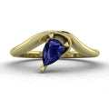 Enchanted pear shaped blue sapphire asymmetric solitaire engagement ring in yellow gold, front view showing deep blue stone and sculptural sweeping band