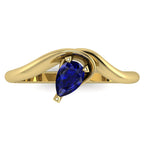 Enchanted pear shaped blue sapphire ring in yellow gold, overhead top-down view showing deep blue stone and fluid asymmetric band design