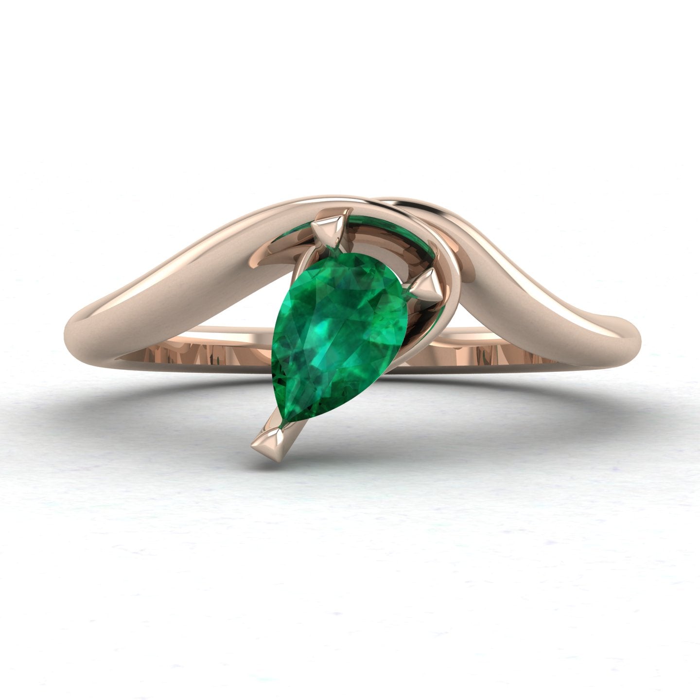 Enchanted pear shaped emerald asymmetric solitaire engagement ring in rose gold, front view showing sculptural sweeping band