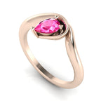 Enchanted pear pink sapphire engagement ring in rose gold, three-quarter angle view showing vibrant pink stone nestled in wrapped asymmetric setting