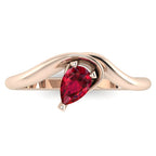 Enchanted pear shaped ruby ring in rose gold, overhead top-down view showing vivid red stone and fluid asymmetric sweeping band design