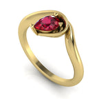Enchanted pear ruby engagement ring in yellow gold, three-quarter angle view showing vivid red stone nestled in asymmetric wrapped setting
