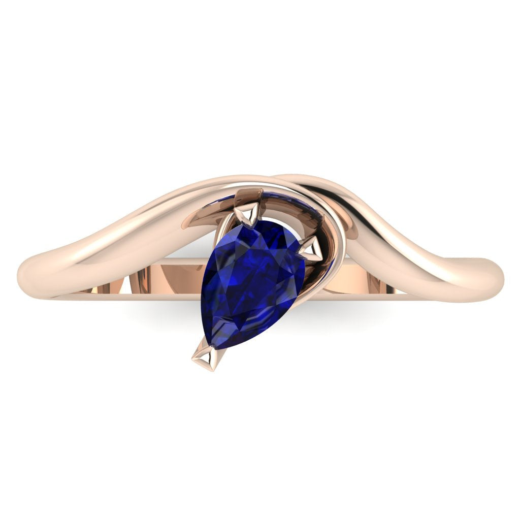 Enchanted pear shaped blue sapphire ring in rose gold, overhead top-down view showing vivid blue stone and fluid asymmetric sweeping band design