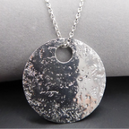 Silver textured handmade glitter ball pendant necklace on a grey surface