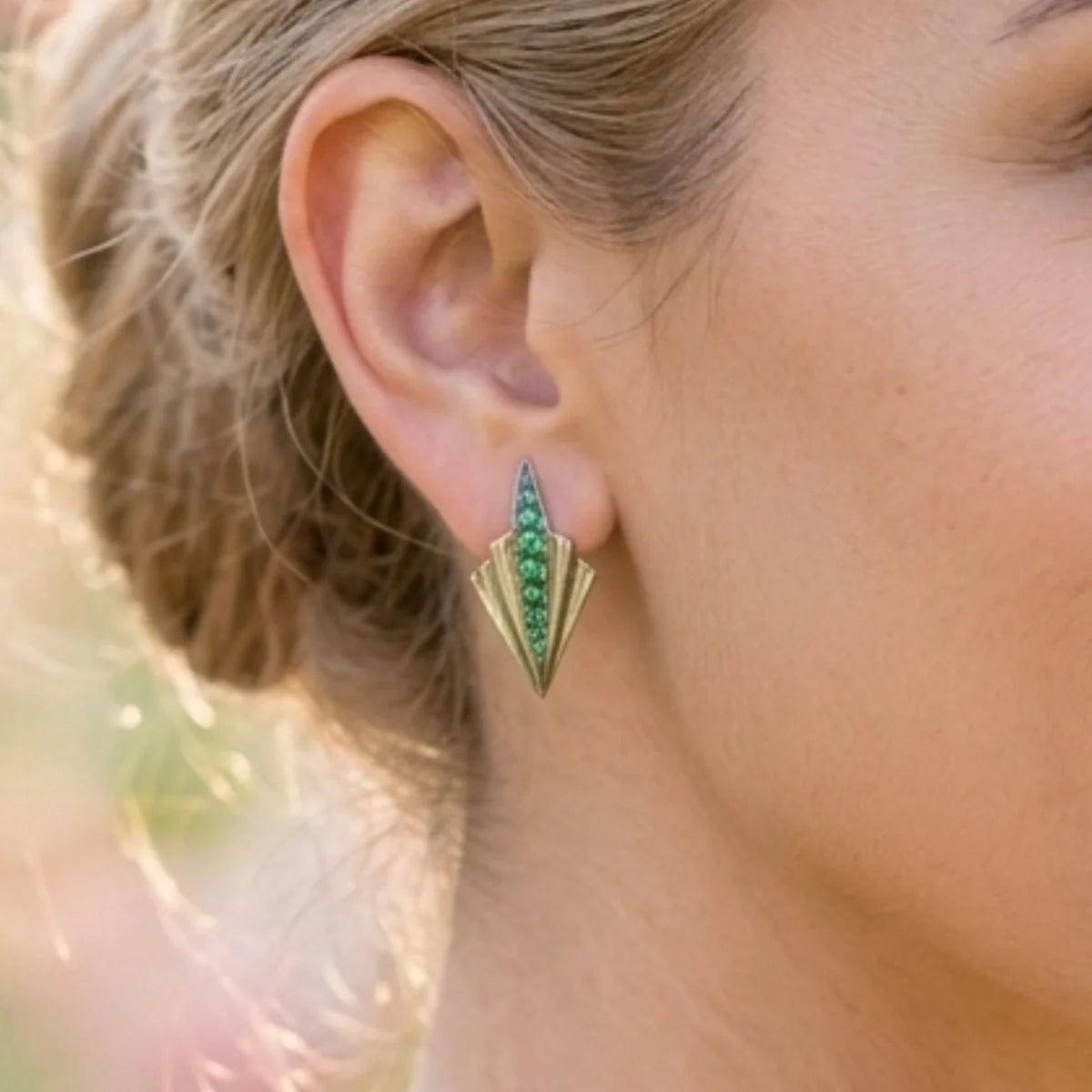 Close-up of Art Deco geometric silver and tsavorite garnet stud earring worn on model, showing green stone detail
