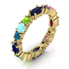 An angled profile view of the Allsorts eternity ring featuring a vibrant mix of blue, pink, and green gemstones in 18ct yellow gold.