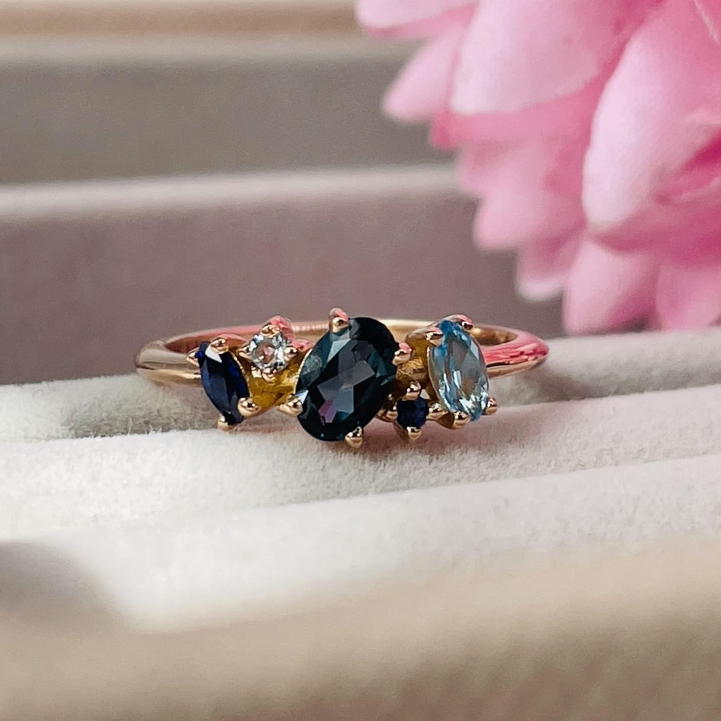 A front view of the Atlantis ring, highlighting the deep blue tones of the gemstones against the warm hue of the 18ct rose gold band.